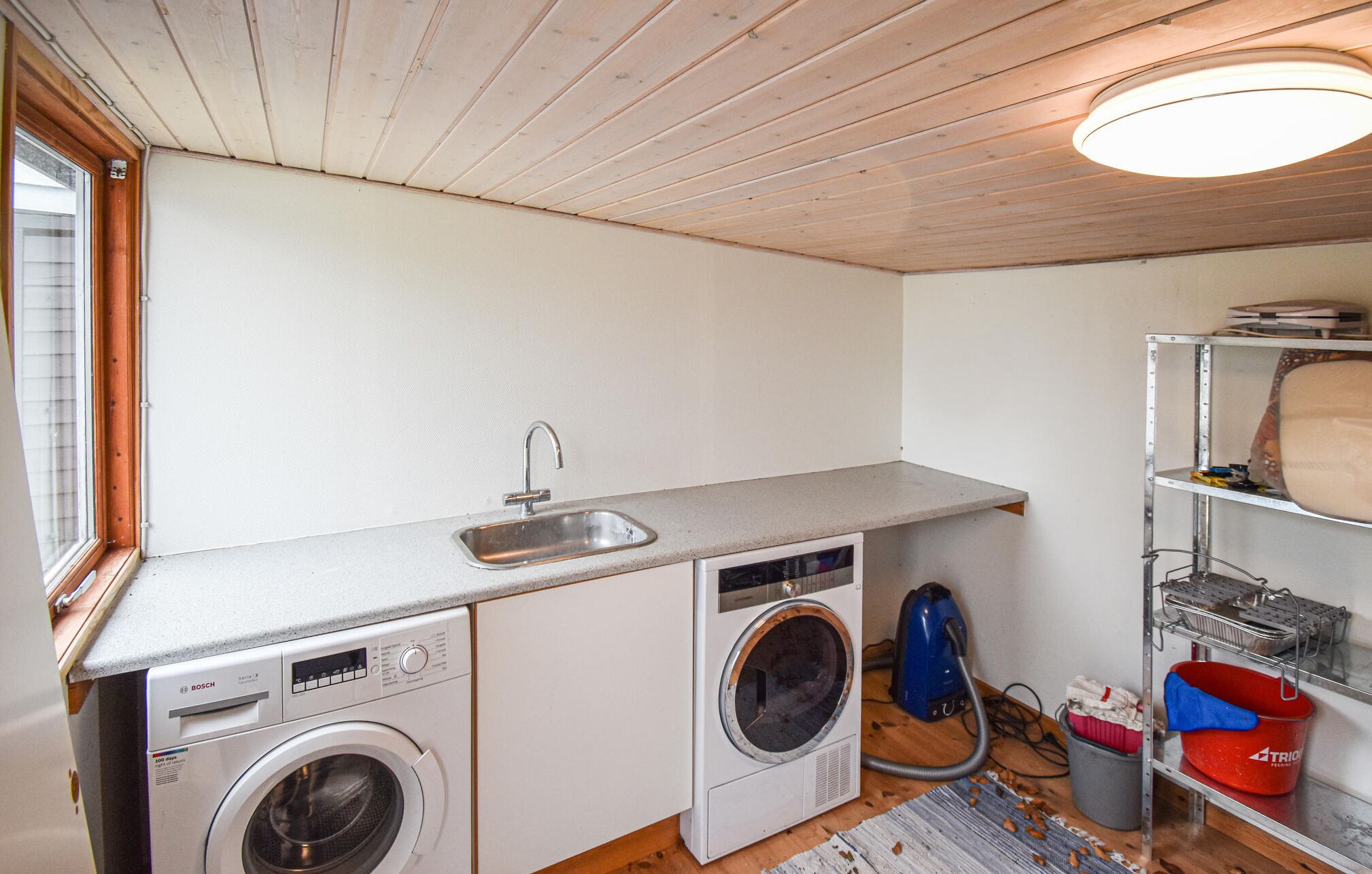 Une petite buanderie équipée d’un lave-linge, d’un sèche-linge et d’un évier.