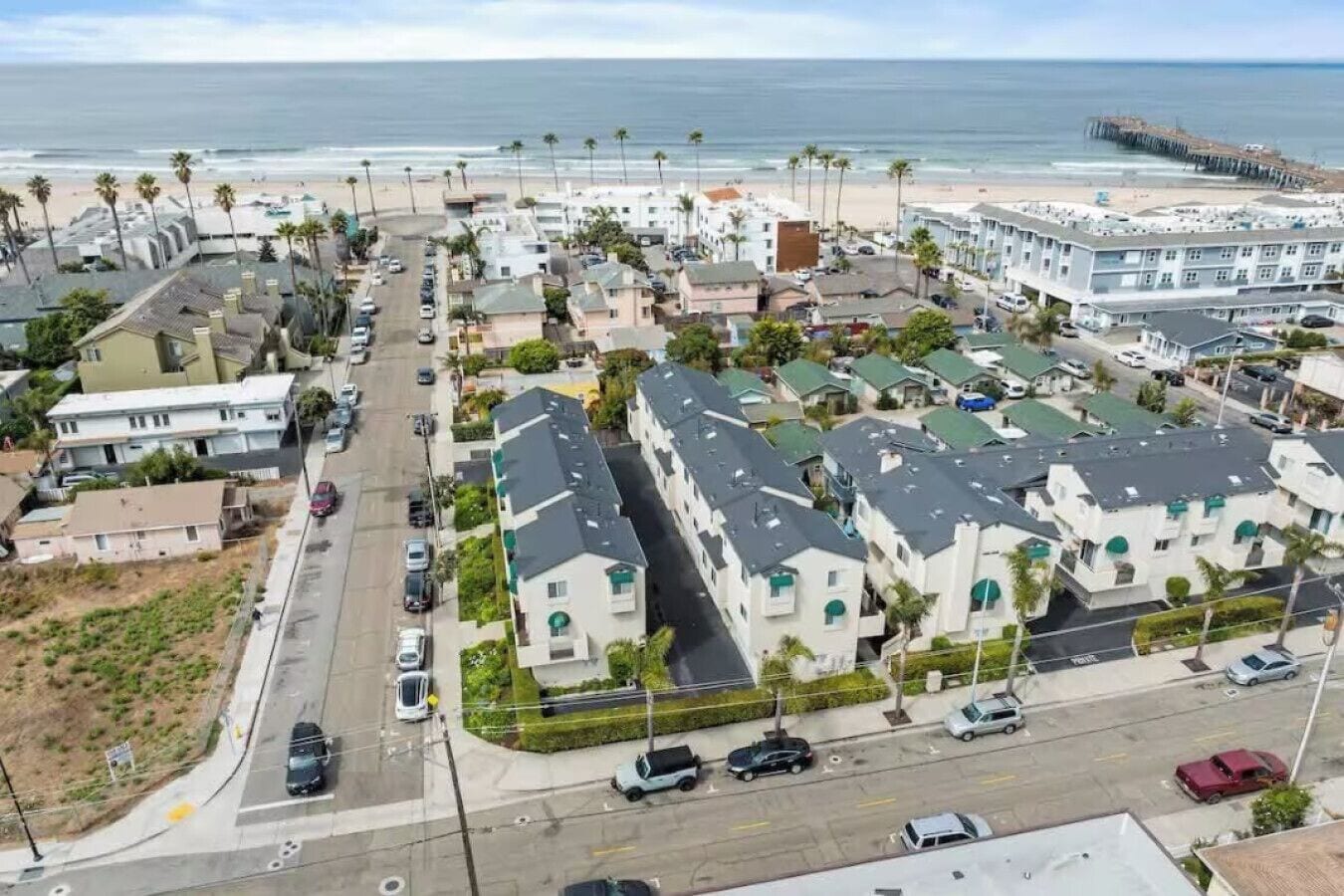 A coastal residential area with modern houses, a beach, and a pier.