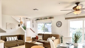 Una sala de estar amplia con sofá, mesa de comedor y ventilador de techo.