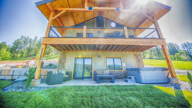 A two-story wooden house with a balcony, outdoor seating, and a hot tub. - Crystal clear Mountain View’s with a farmhouse chic vibe. (Sturgis)