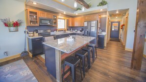 A modern kitchen with a large island, wooden cabinets, stainless steel appliances, and a wooden ceiling. - Crystal clear Mountain View’s with a farmhouse chic vibe. (Sturgis)