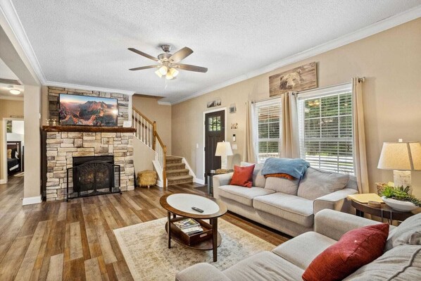 A living room with a stone fireplace, a ceiling fan, a sofa, and a coffee table.