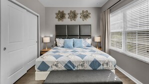 A bedroom with a bed, bedside lamps, a bench, and decorative wall art. - Spacious3 bdr w/ private jacuzzi private jacuzzi! (Kissimmee)