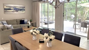 A modern living room with a sofa, coffee table, and dining table set with white flowers. - Spacious3 bdr w/ private jacuzzi private jacuzzi! (Kissimmee)