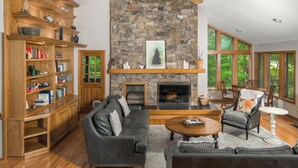 Una sala de estar con chimenea, estantes de madera, un sofá y un sillón.