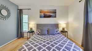 Un dormitorio con una cama grande, dos mesitas de noche, un espejo colgado en la pared y un cuadro de un barco en un muelle.