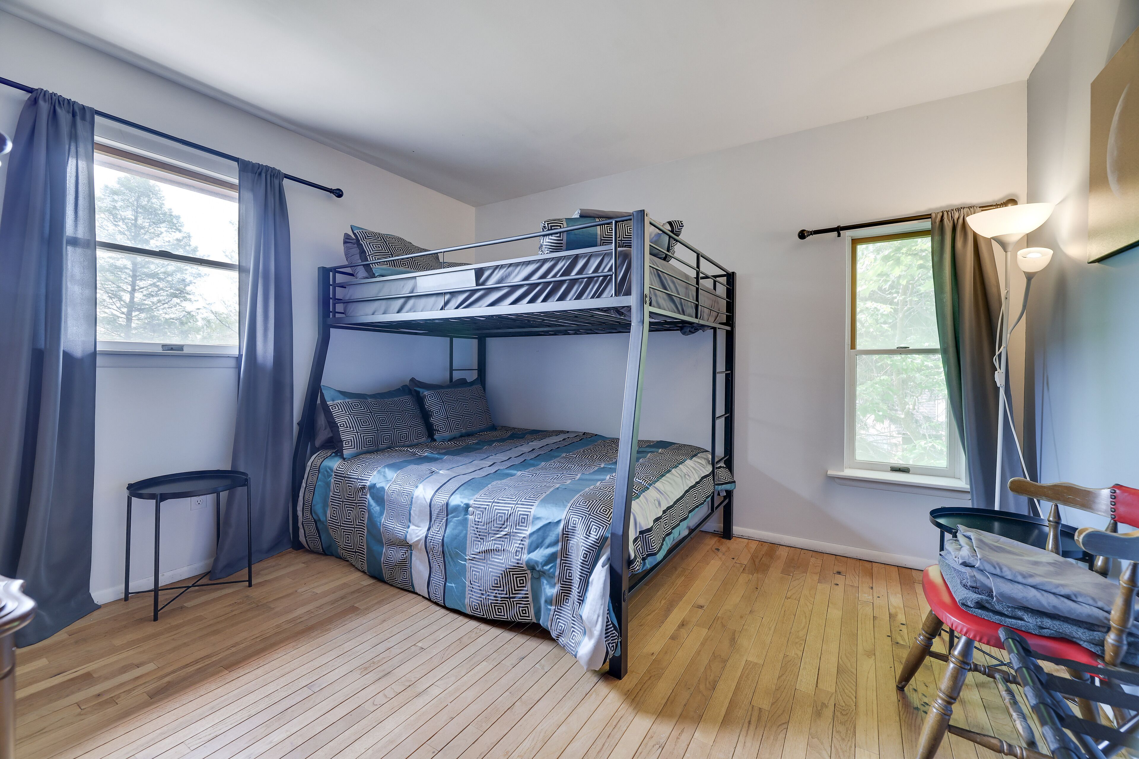 Une chambre avec un lit superposé, un plancher en bois, une petite table et une chaise.