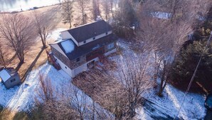 Una casa de dos pisos con fachada de piedra, un garaje amplio y un patio cubierto de nieve.