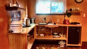 A compact kitchen with a coffee maker, kettle, and a small sink.