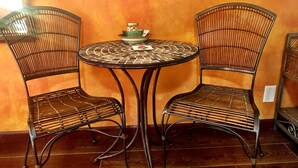 A round table with a woven metal frame, flanked by two wicker chairs with metal legs.