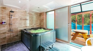 A bathroom with a hot tub, a shower, and a glass door leading to an outdoor area with a picnic table. - Kkoristar Pool and Spa Pension (Gapyeong)