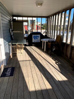 A covered porch with a grill, a table, and chairs. - “The Fishbowl” - The Perfect Surf City Intimate Beach Cottage! (Surf City)