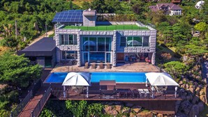 A modern house with a large swimming pool, a covered deck, and a stone facade. - Miramonti Pool Villa Pension (Gapyeong)