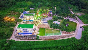 An aerial view of a resort with multiple buildings, a swimming pool, and landscaped gardens. - Miramonti Pool Villa Pension (Gapyeong)