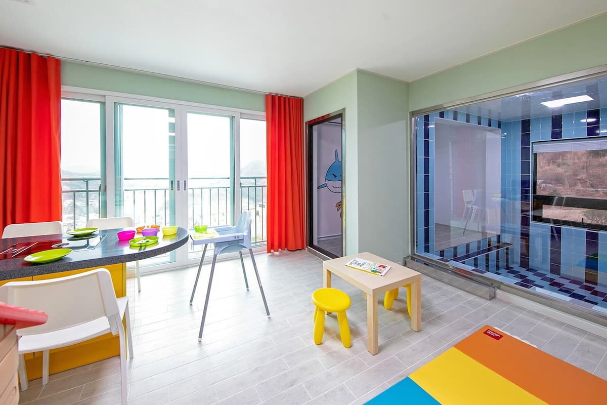Een kinderspeelruimte met een tafel, stoelen en een klein krukje.