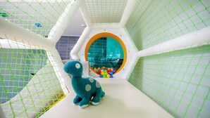 Un espace de jeux avec une enceinte grillagée, une piscine à balles et des peluches.