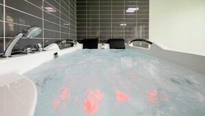 Une salle de bain moderne avec une grande baignoire, deux robinets et un mur recouvert de carreaux.