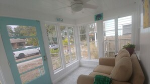 A sunroom with a teal door, a beige sofa, and a potted plant. - Cute Bungalow in Historic Kenwood (St. Petersburg)