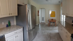 A modern kitchen with stainless steel appliances, white cabinets, and a granite countertop. - Cute Bungalow in Historic Kenwood (St. Petersburg)