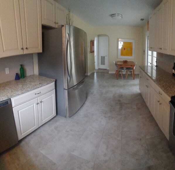 A modern kitchen with stainless steel appliances, white cabinets, and a granite countertop.