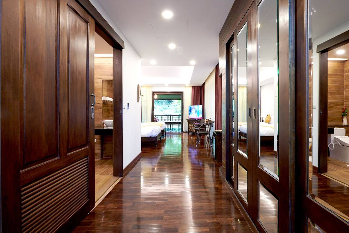 Un pasillo de hotel con suelo de madera, un televisor en la habitación y una cama con ventana.