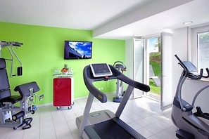 A fitness room with a treadmill, exercise bike, and stationary bike.