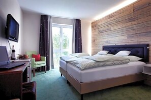 Une chambre d’hôtel avec un lit, un bureau avec un ordinateur portable, une télévision et une fenêtre avec des rideaux.