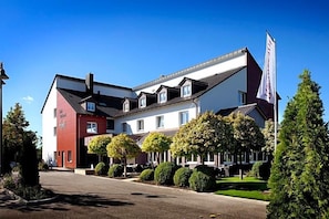 A hotel with a red and white facade, multiple windows, and a flag.