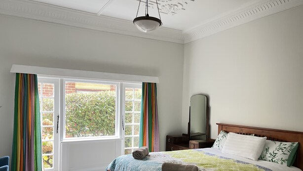 Un dormitorio con cama, cómoda, espejo y ventana con cortinas.