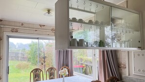 Un comedor con una mesa, sillas, un florero con flores y vistas al exterior.