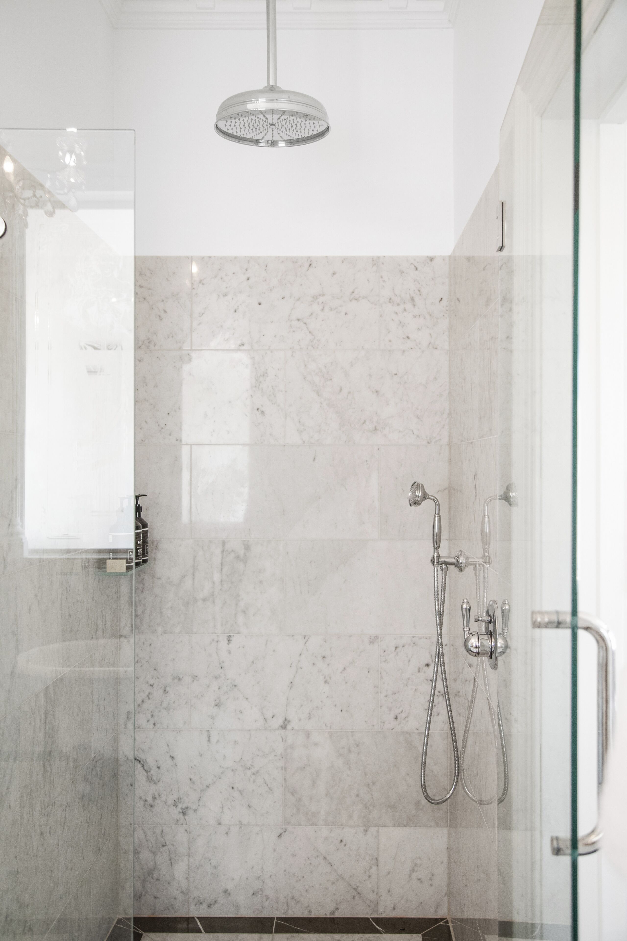 A modern shower with a handheld showerhead and a wall-mounted faucet.
