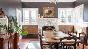 Comedor con una gran mesa de madera, bancos acolchados y chimenea.