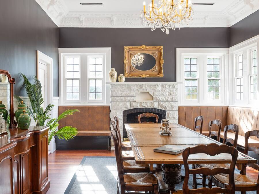 A dining room with a large wooden table, cushioned benches, and a fireplace.