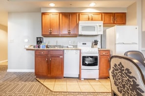 Compact kitchen with microwave, oven, and refrigerator, adjacent to a cozy seating area.