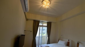 A hotel room with two beds, a ceiling light, and a sliding glass door leading to an outdoor area. - Light Time B&B (Hualien City)
