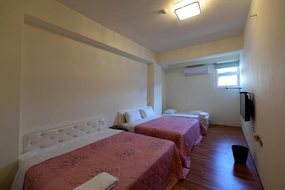 A room with two beds, a television, and a window.