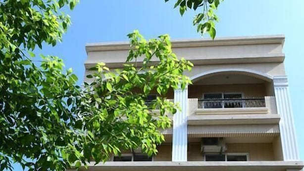 A multi-story building with a beige facade, a balcony on the second floor, and a street lamp with a sign displaying the number 220. - Light Time B&B (Hualien City)