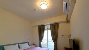 A bedroom with a bed, a bedside table, a window with curtains, and an air conditioning unit. - Light Time B&B (Hualien City)