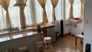 A compact living space with a kitchen area, wooden flooring, and a dining area with stools. - Costa Rica: Studio Close to EVERYTHING (Heredia)