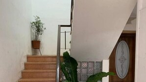 A staircase with a handrail, a potted plant at the top, and a tiled floor. - Costa Rica: Studio Close to EVERYTHING (Heredia)