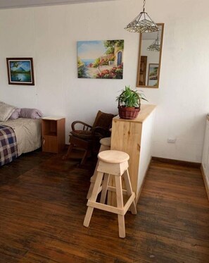 Cozy retreat with a plush bed, wooden stool, and charming artwork.