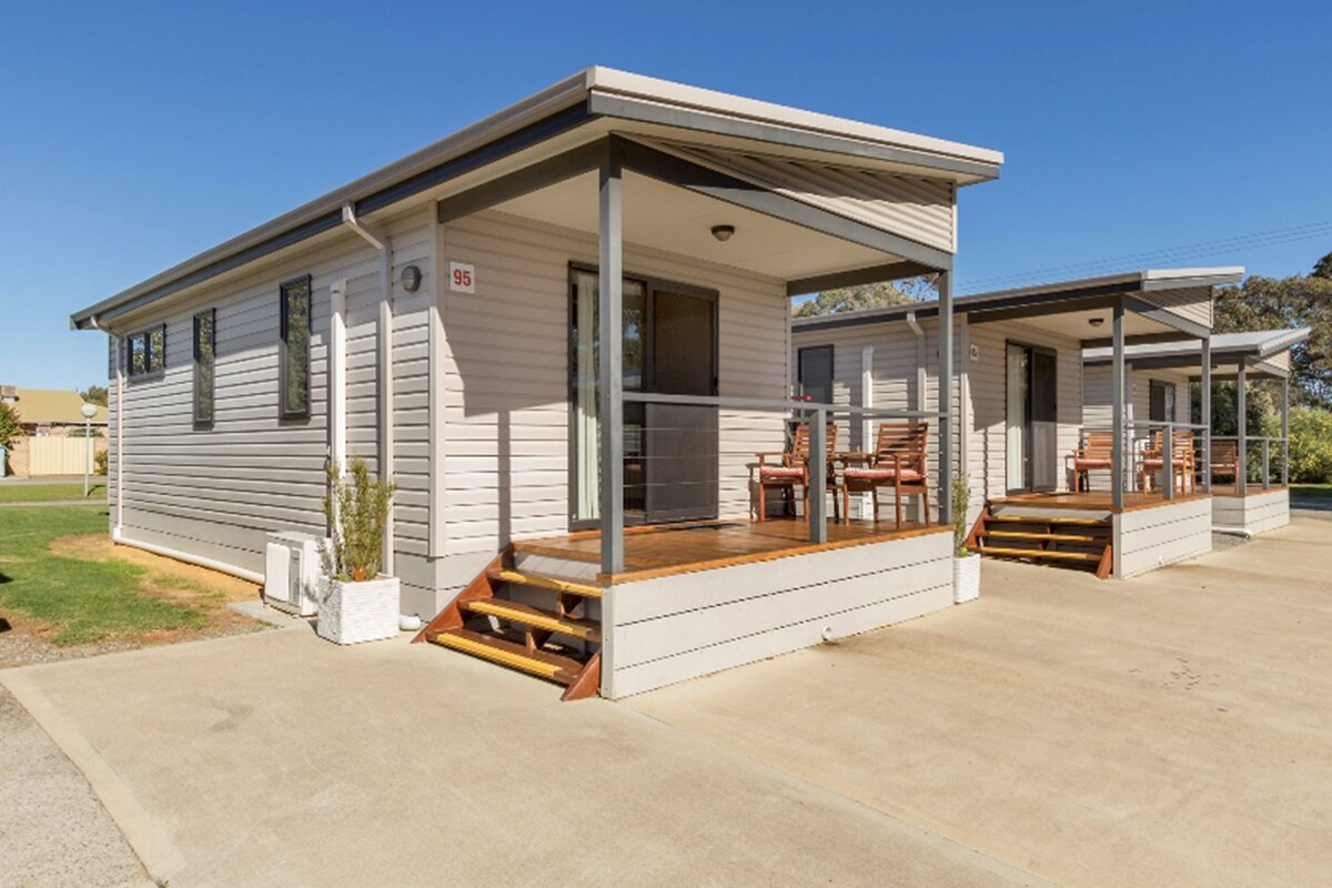 A single-story mobile home with a covered porch and outdoor seating area.