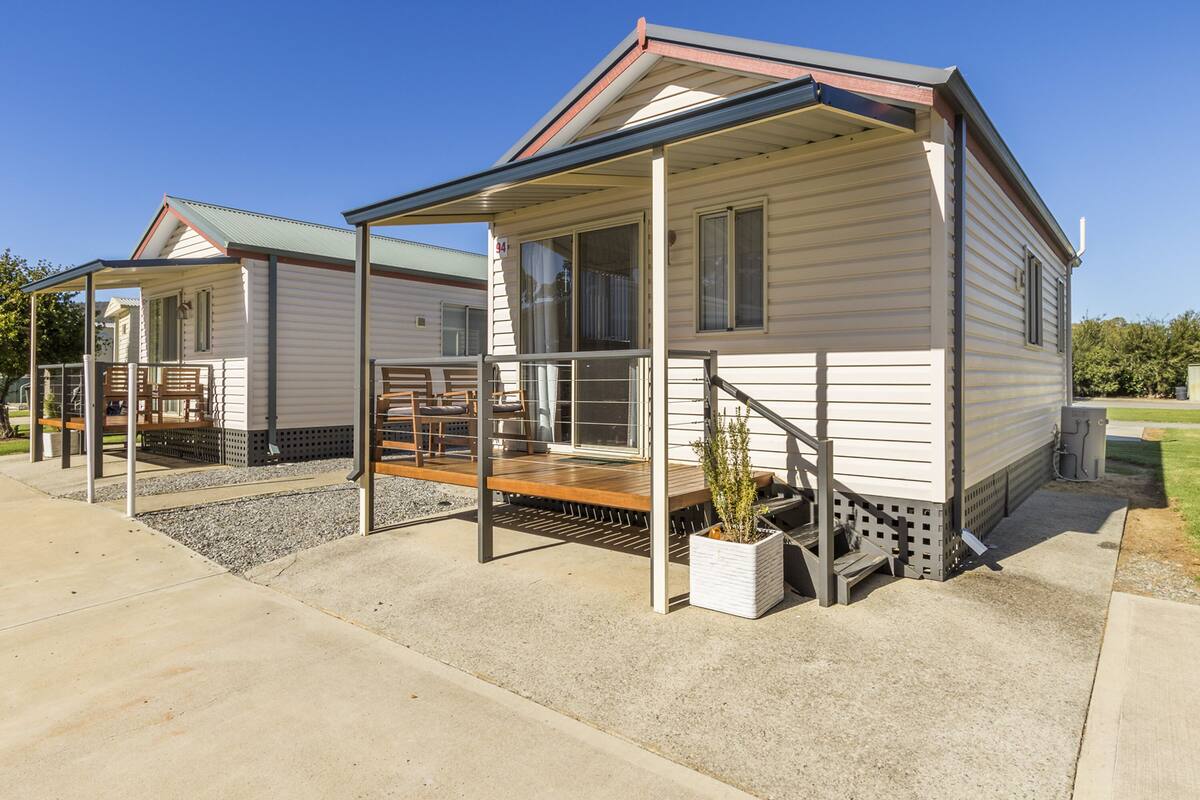 A row of mobile homes with covered porches and outdoor seating areas.