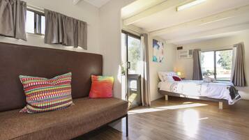 A room with a sofa, a bed, and a window with curtains.