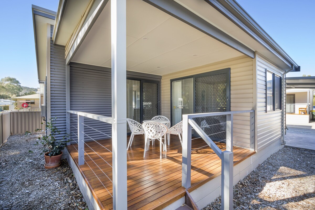 A modern house with a wooden deck, white outdoor furniture, and a covered porch area.