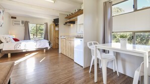 Un dormitorio con cama, una kitchenette pequeña y una zona de comedor con mesa y sillas.