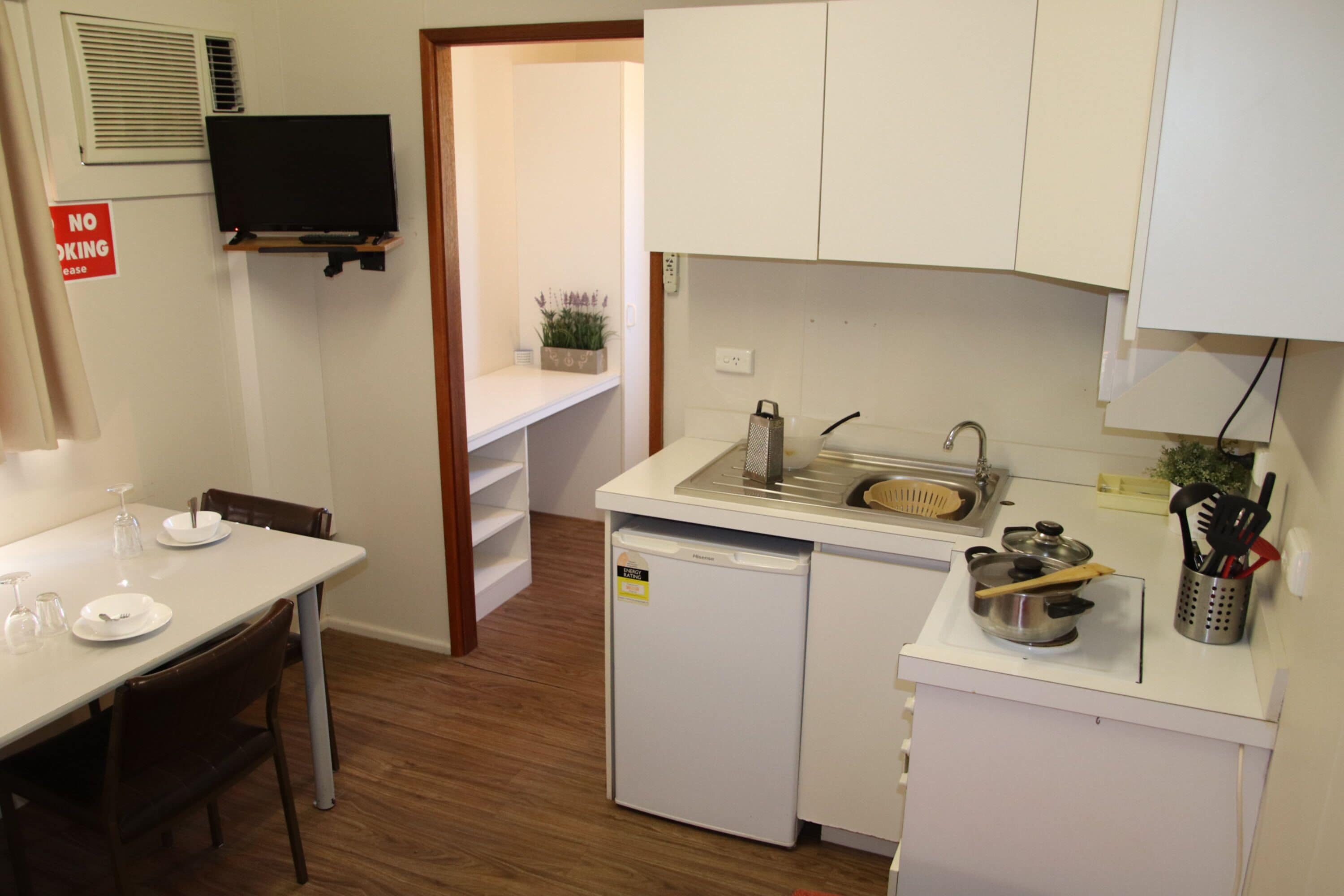 Una cocina compacta con un lavabo, un refrigerador pequeño y una zona de comedor con sillas y una mesa.