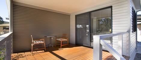 A covered outdoor area with a wooden deck, two wooden chairs, and a table.