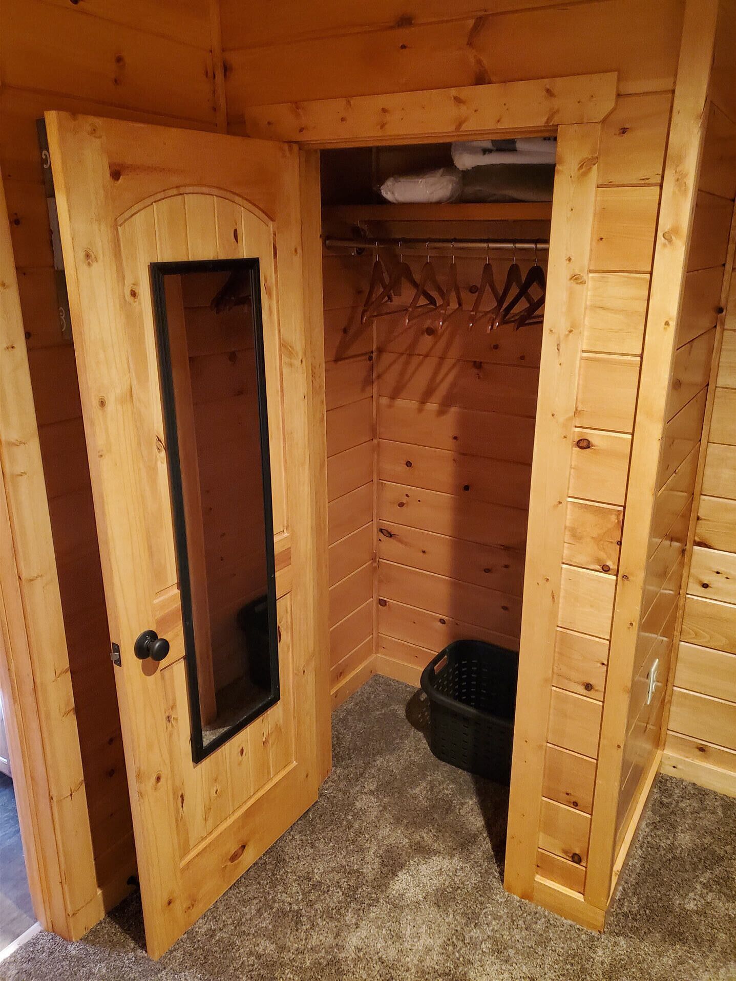 A wooden room with a door, a coat rack, and a small basket.