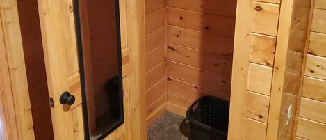 A wooden room with a door, a coat rack, and a small basket.